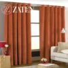 Luxury rust orange velvet eyelet curtains hanging in a bright living room, showcasing a soft matte texture and deep uniform folds.